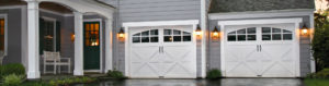 white garage doors with arched windows on gray house