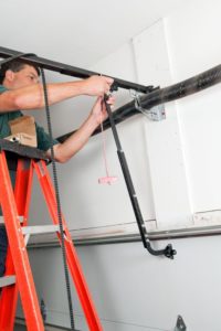 technician performing seasonal garage door maintenance